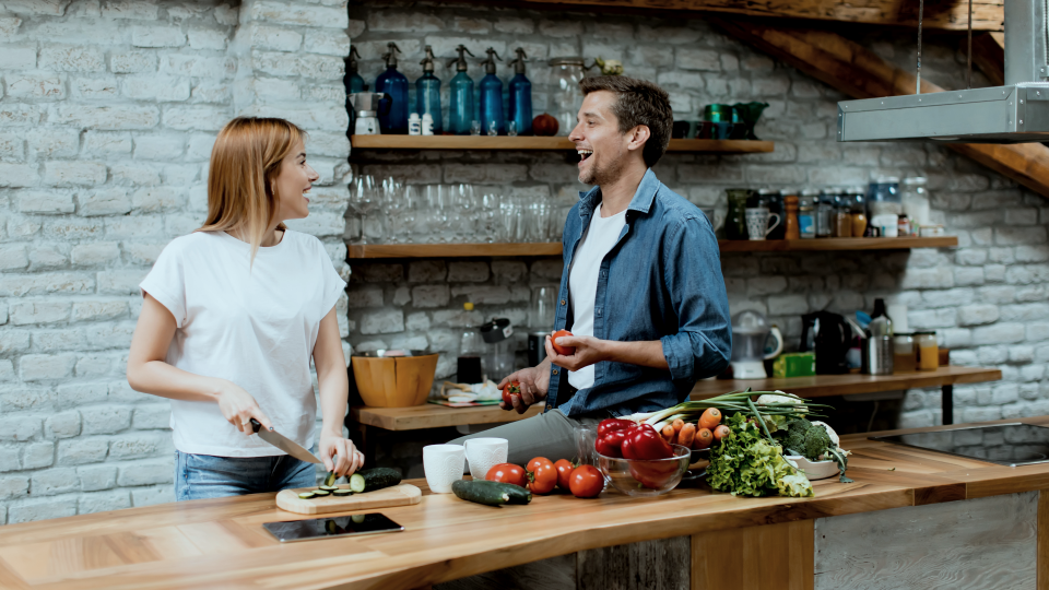 Young couple slicing vegetables in rustic kitchen 