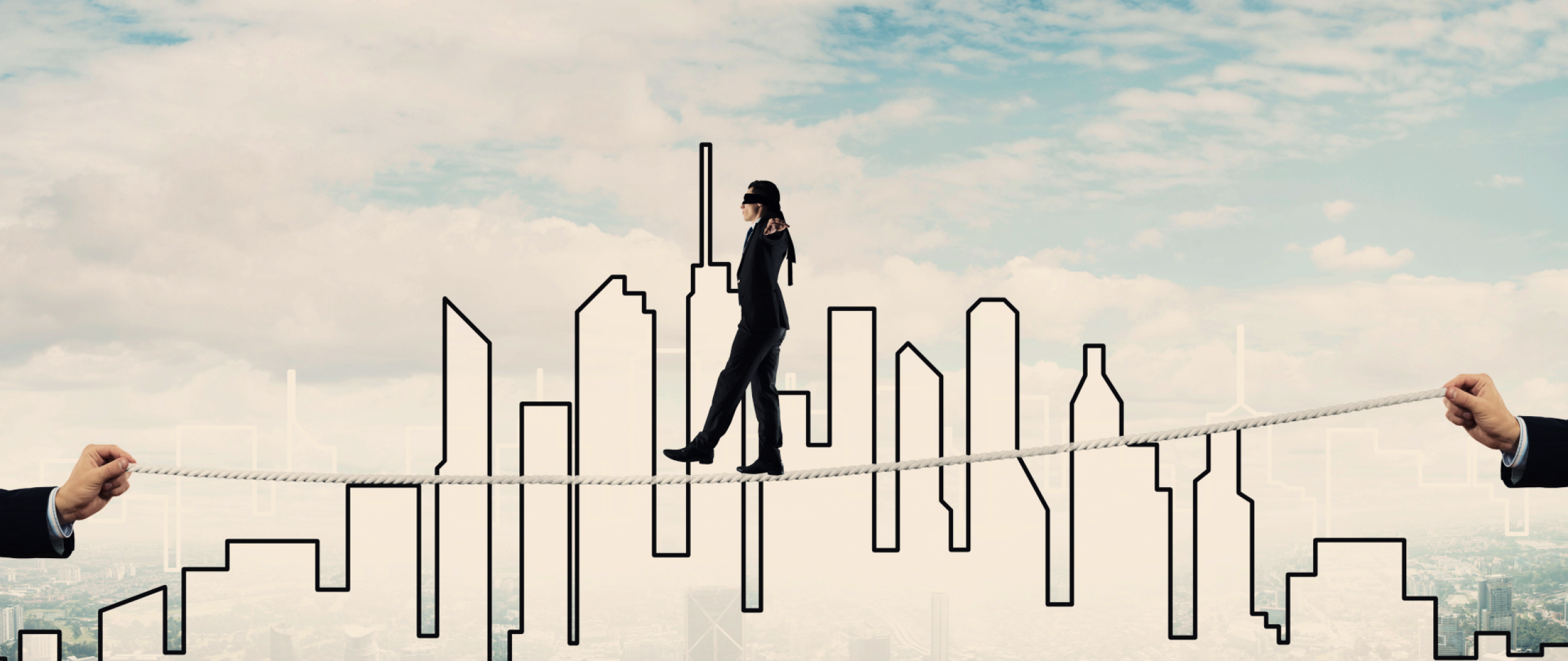 Blindfolded business person walking a tightrope with a cityscape in the background 