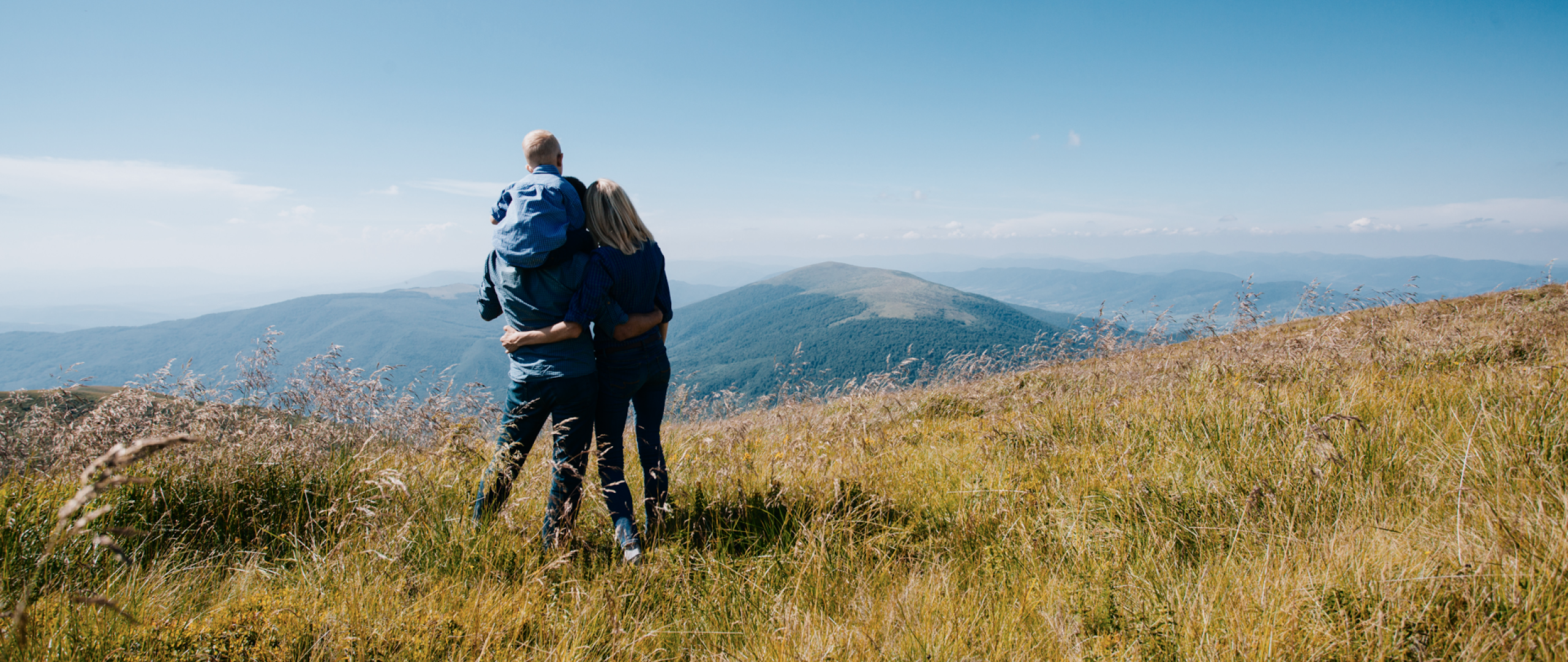 Couple standing on hill top looking at mountains in the distance 