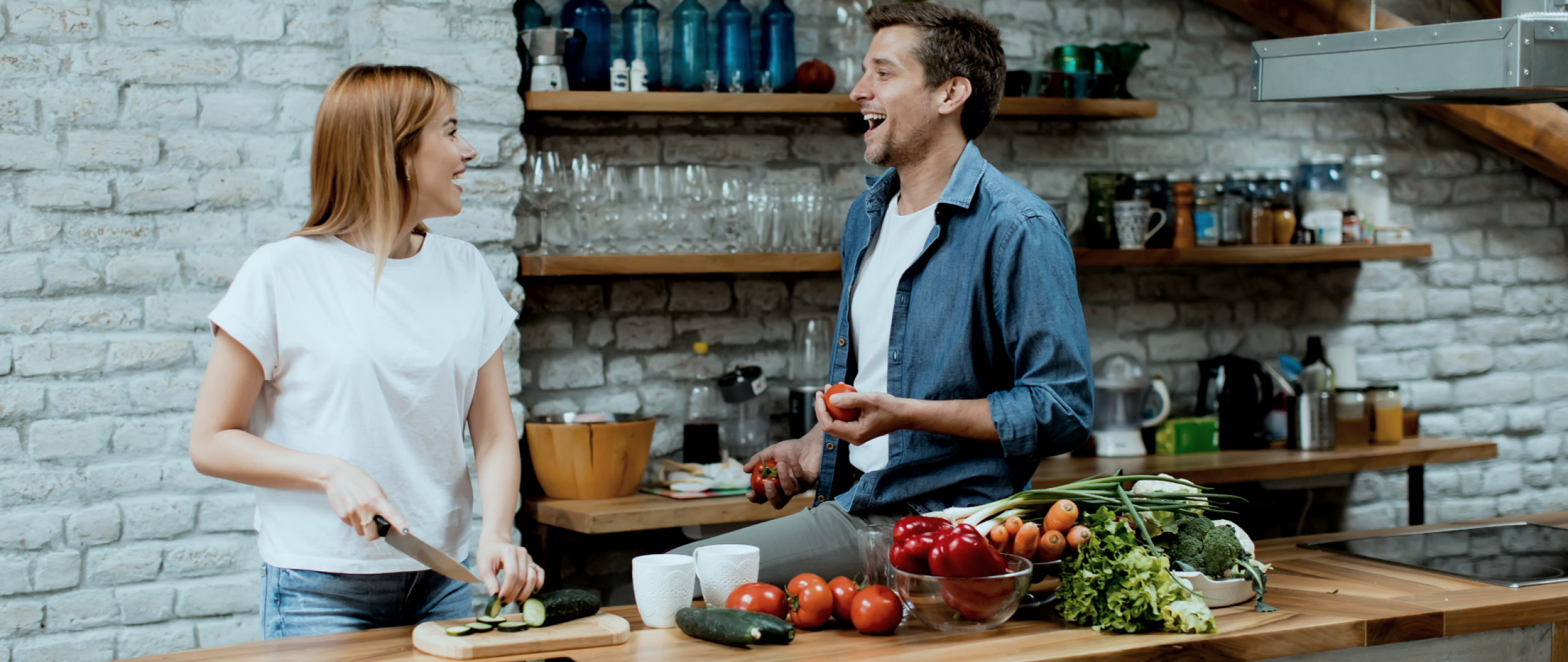 Young couple slicing vegetables in rustic kitchen 