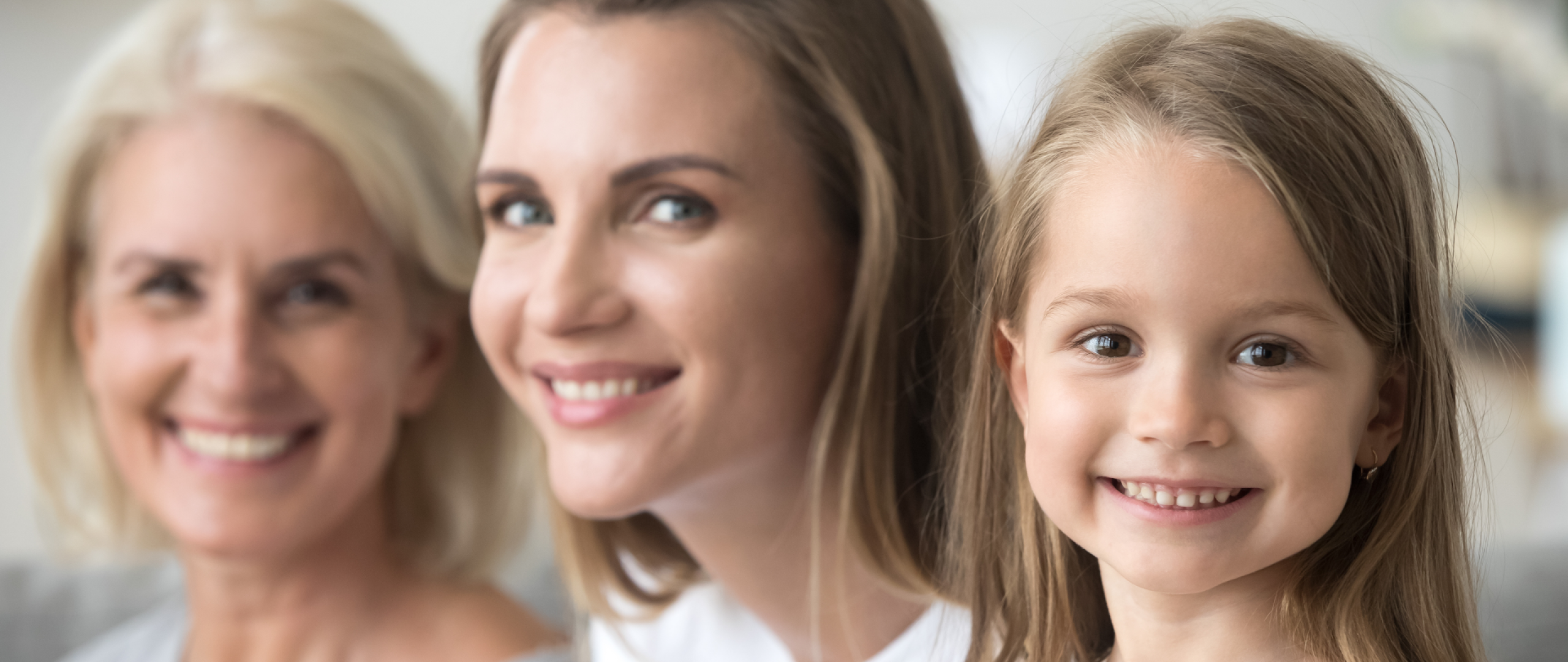 Three generations of women with young girl in focus on right, her mother partially out of focus in middle, and her mother blurred on the right